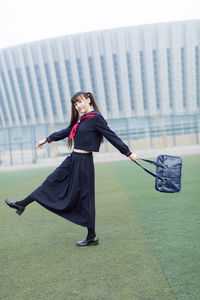 Woman with bag standing on field