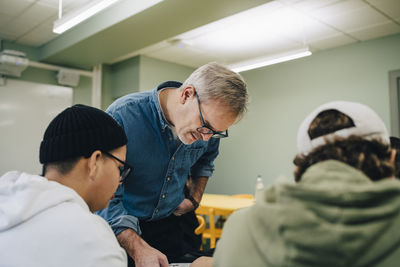 Male teacher teaching students in classroom