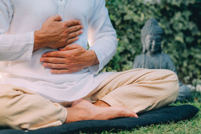 Male therapist performing reiki therapy self treatment holding hands over his stomach. 