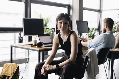 Portrait of non-binary business person sitting on chair at new office