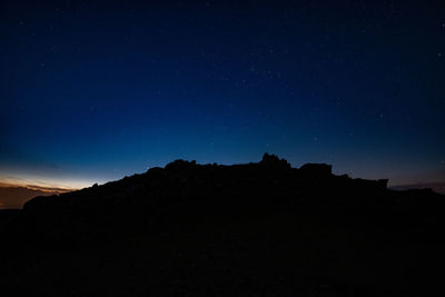 Low angle view of silhouette mountain against sky at night