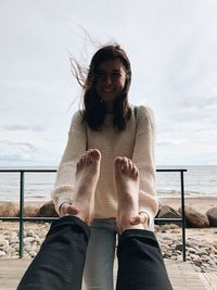 Woman pulling legs of man against beach