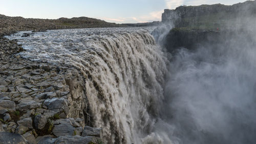 Scenic view of waterfall against sky