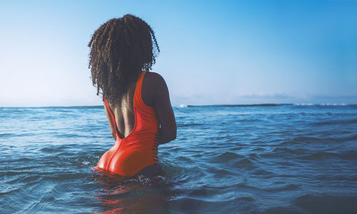 Rear view of woman in sea against sky