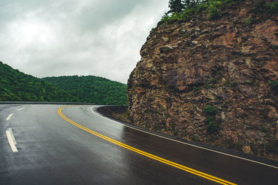 Empty road by mountain against sky