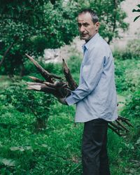 Side view portrait of man holding wood on field