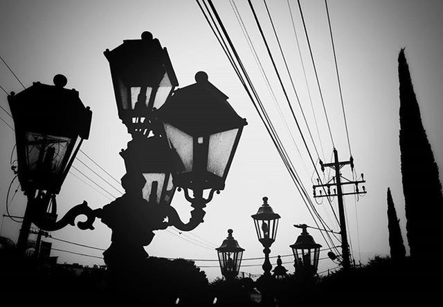 low angle view, lighting equipment, silhouette, electricity, street light, cable, hanging, power line, clear sky, sky, lantern, electric light, built structure, power supply, technology, fuel and power generation, lamp post, pole, dusk, electric lamp