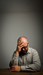 Portrait of man sitting on table against wall