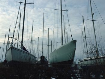 Sailboats in sea against cloudy sky