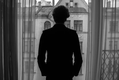 Rear view of man standing on window balcony