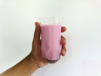 Cropped hand of woman holding drink against white background