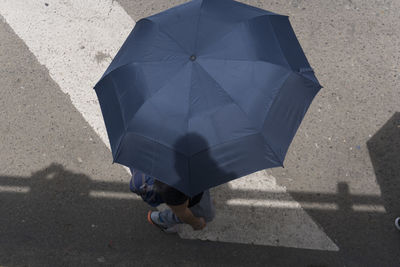 High angle view of man walking with umbrella on street