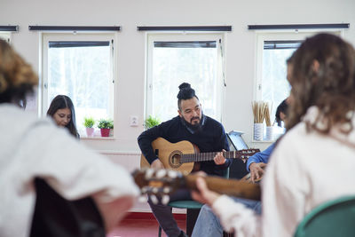 Teenagers attending guitar lesson