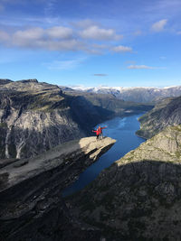 Distant view of couple standing on cliff against mountain range