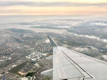 Cropped image of airplane wing flying over cityscape