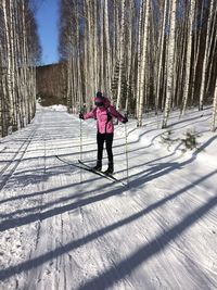 Full length of young woman skiing on snow covered field in forest