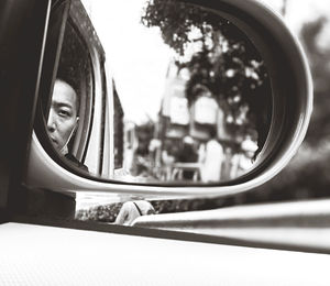 Portrait of man seen through side view mirror