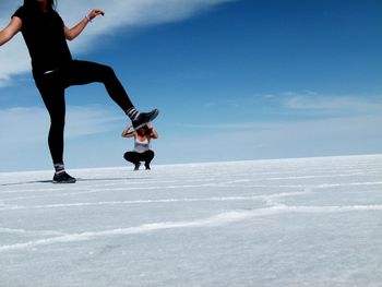 Optical illusion of woman pressing friend with foot at salar de uyuni