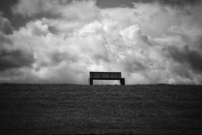 Bench on field against sky
