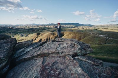 Man standing on rock against sky