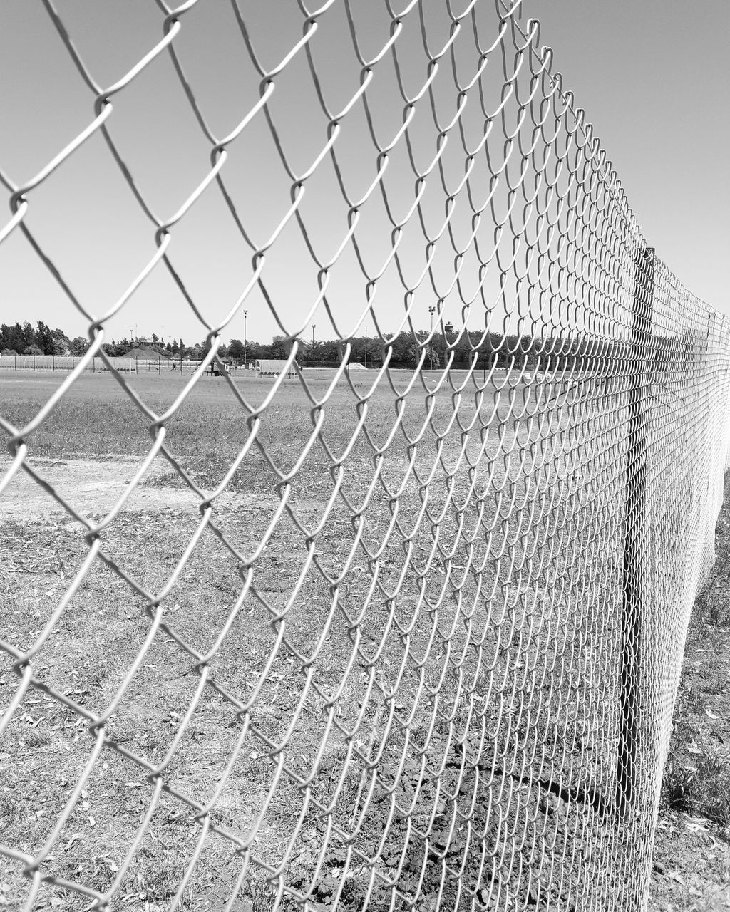 CLOSE UP OF CHAINLINK FENCE AGAINST SKY