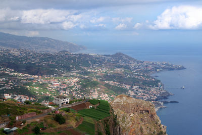 Aerial view of city by sea against sky