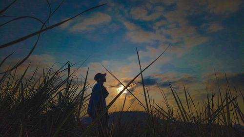 Silhouette man standing on field against sky during sunset