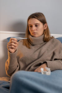 Sick woman checking temperature at home