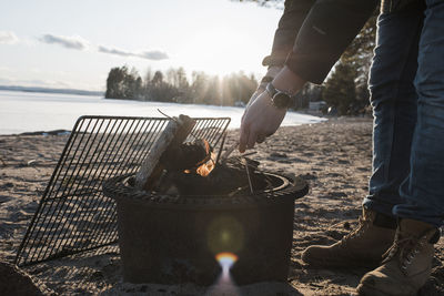 Man's hands lighting a bonfire outside on a beach in sweden