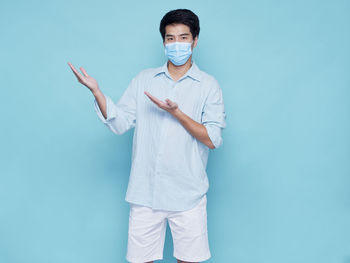 Portrait of man standing against blue background