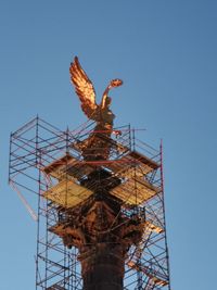 Low angle view of crane against clear blue sky