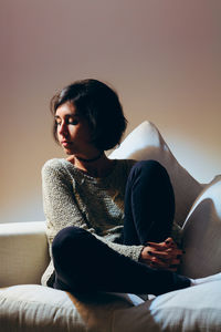 Young woman sitting on sofa at home