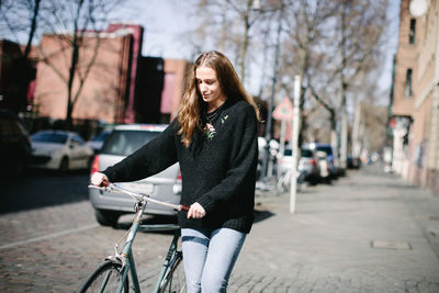 Young woman with bicycle on street in city