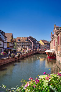 Scenic view of river by buildings against blue sky