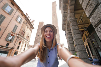Attractive tourist girl takes self portrait with bologna two towers landmark, italy
