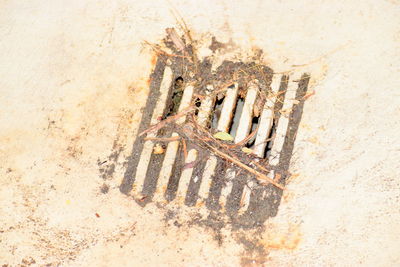 High angle view of rusty metal grate against wall