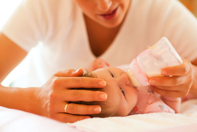 Midsection of woman feeding baby on bed