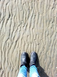 Low section of man standing on sand