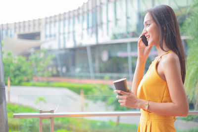 Woman looking away while standing on mobile phone