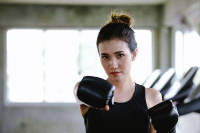 Portrait of young woman punching at gym