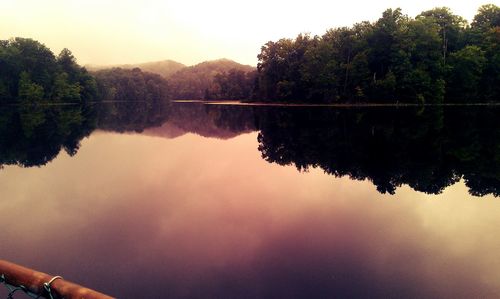 Reflection of silhouette trees in lake against sky