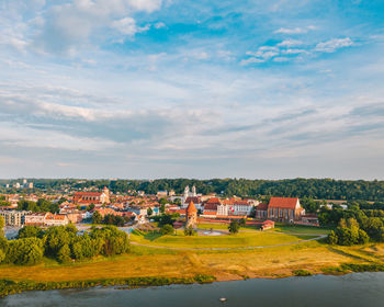 Houses on field by buildings against sky