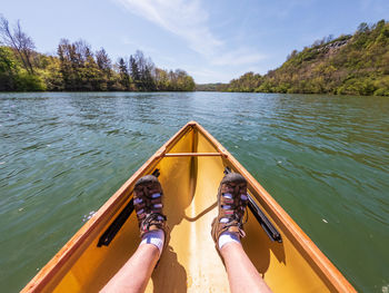 Low section of man on boat in lake against sky