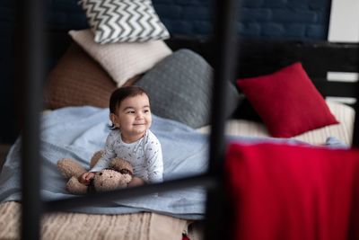 Cute baby girl sitting on toy at home