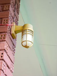 Low angle view of illuminated light bulb hanging on ceiling in building