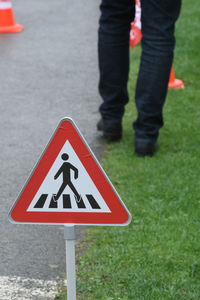 Low section of person standing by road sign