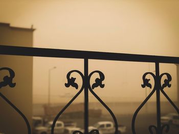 Close-up of metal railing against sky during sunset