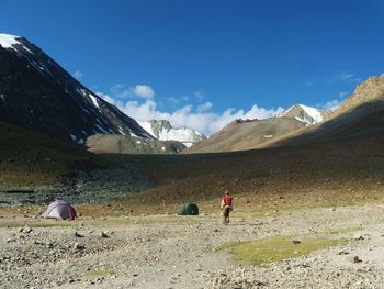 Rear view of man with tents on field at himalayas against sky