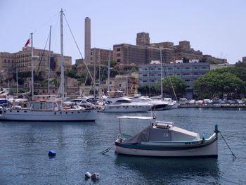 Sailboats moored in sea against buildings in city
