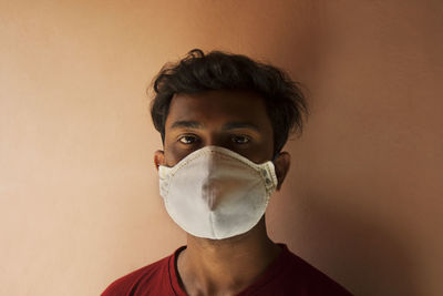 Portrait of young man with mask against wall